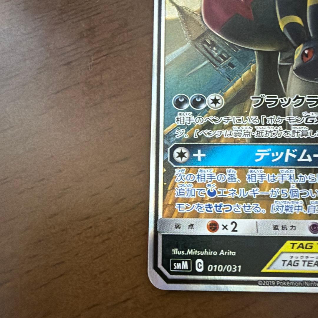 Bastus Black & Darkrai GX trading card with minor wear, displayed on a shelf