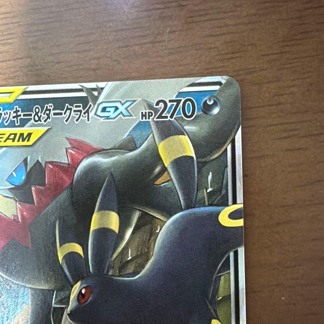 Bastus Black & Darkrai GX trading card with minor wear, displayed on a shelf