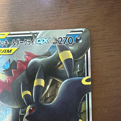 Bastus Black & Darkrai GX trading card with minor wear, displayed on a shelf