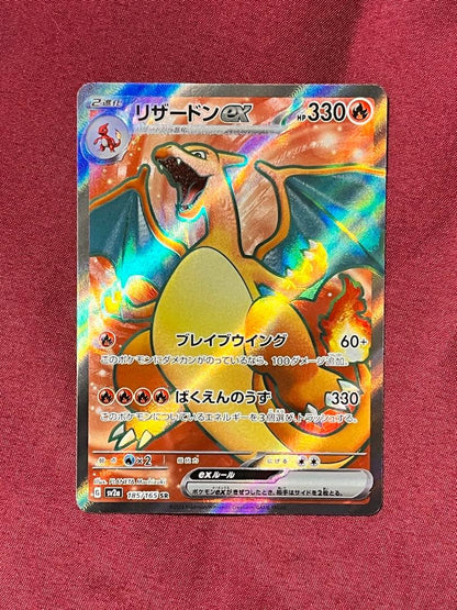 Close-up of Pokemon Charizard EX SV2A SR 185/165 trading card in protective sleeve and rigid loader