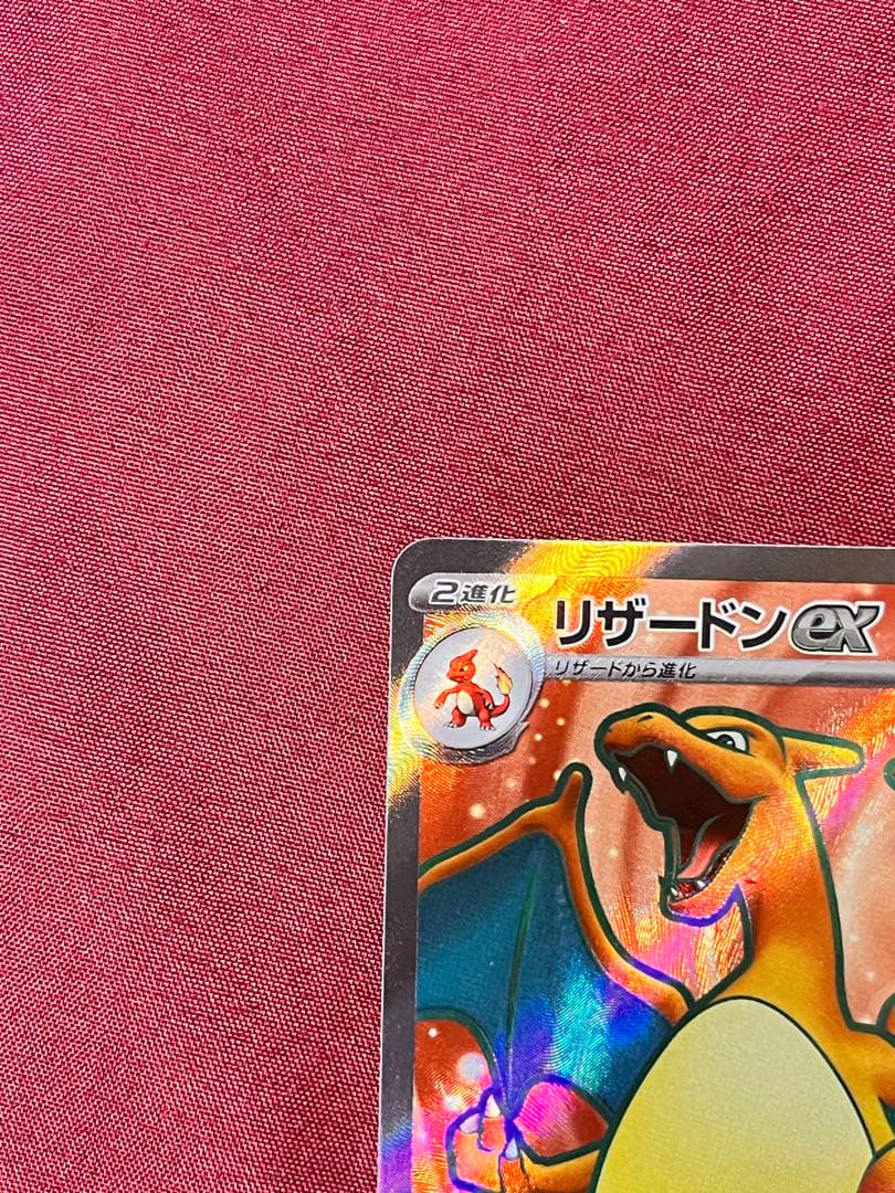 Close-up of Pokemon Charizard EX SV2A SR 185/165 trading card in protective sleeve and rigid loader