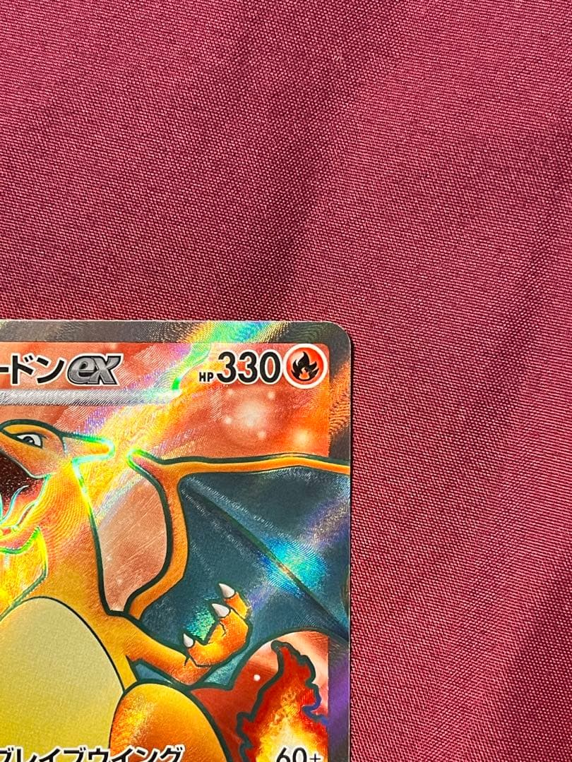 Close-up of Pokemon Charizard EX SV2A SR 185/165 trading card in protective sleeve and rigid loader
