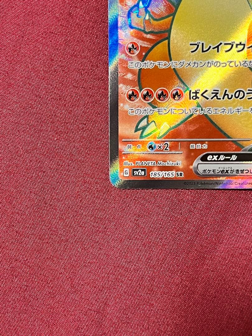 Close-up of Pokemon Charizard EX SV2A SR 185/165 trading card in protective sleeve and rigid loader