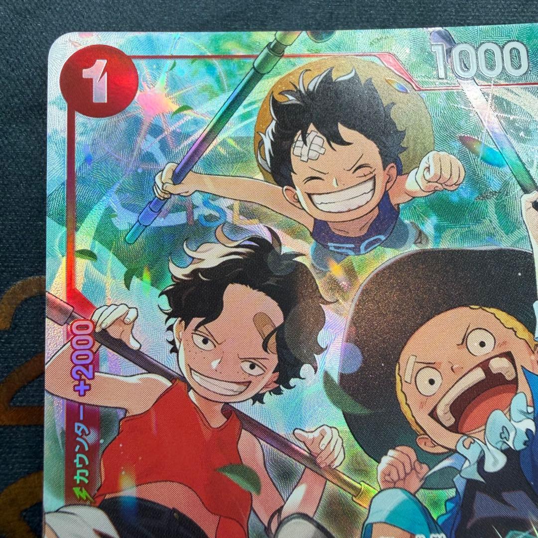 One Piece OP13-007 SR parallel figure card showing Ace, Sabo, and Luffy in PSA sleeve