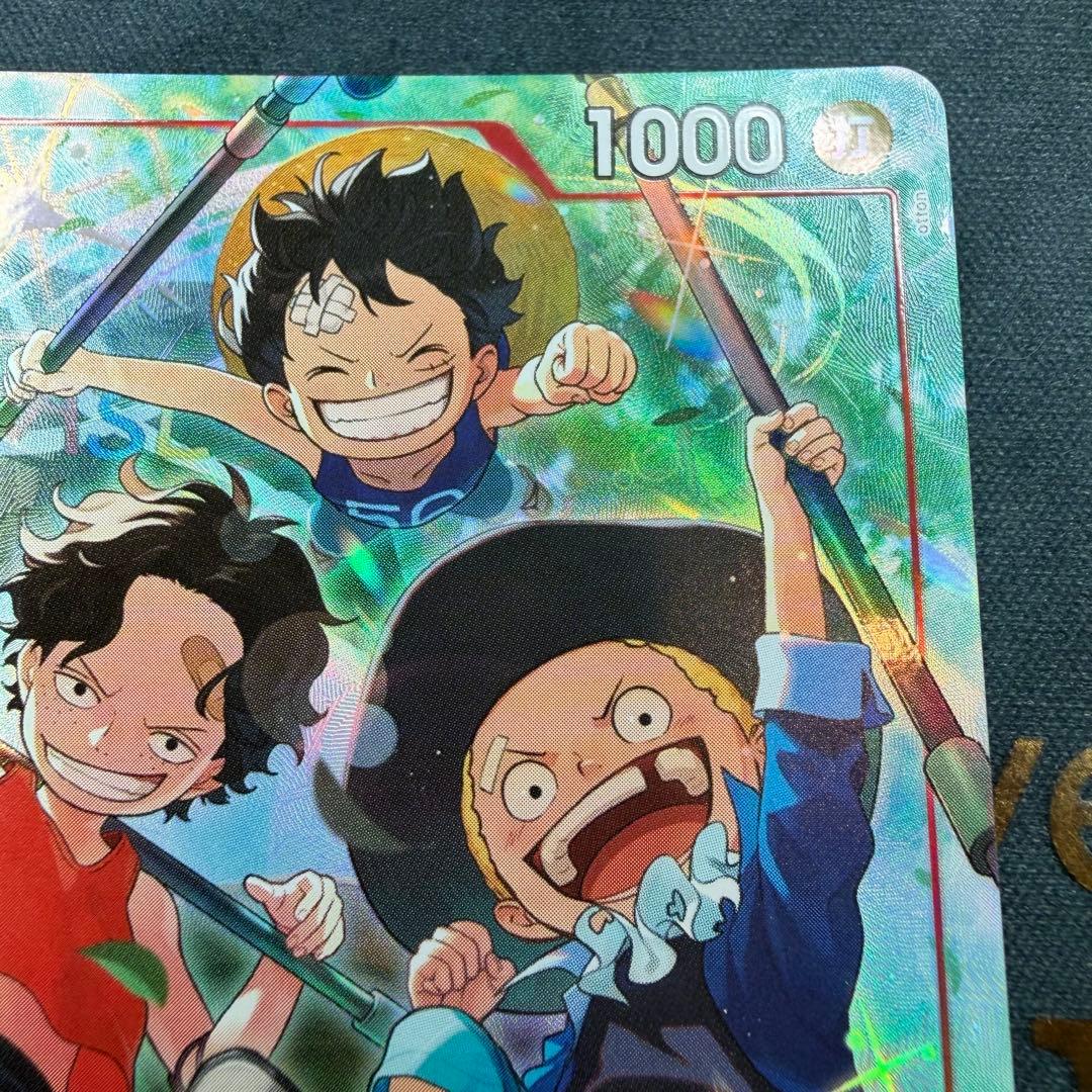 One Piece OP13-007 SR parallel figure card showing Ace, Sabo, and Luffy in PSA sleeve