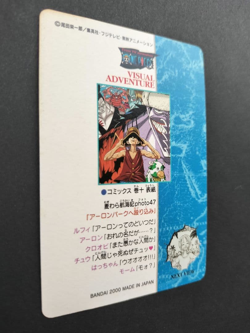 One Piece Carddass Visual Adventure 61 trading card showing Arlong Park with slight edge wear and sun fading on the back
