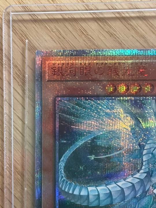 Yu-Gi-Oh Galaxy Eyes Afterglow Dragon 20th trading card with visible scratches and wear in protective loader