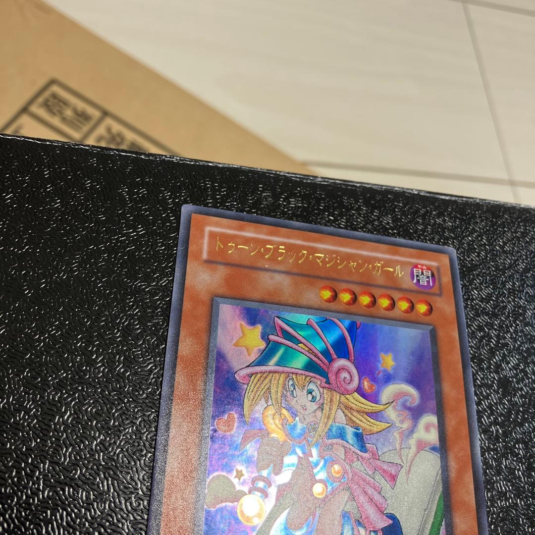 Bandai Toon Black Magician Girl Ultra Rare trading card showing visible wear, dents, creases, and chips
