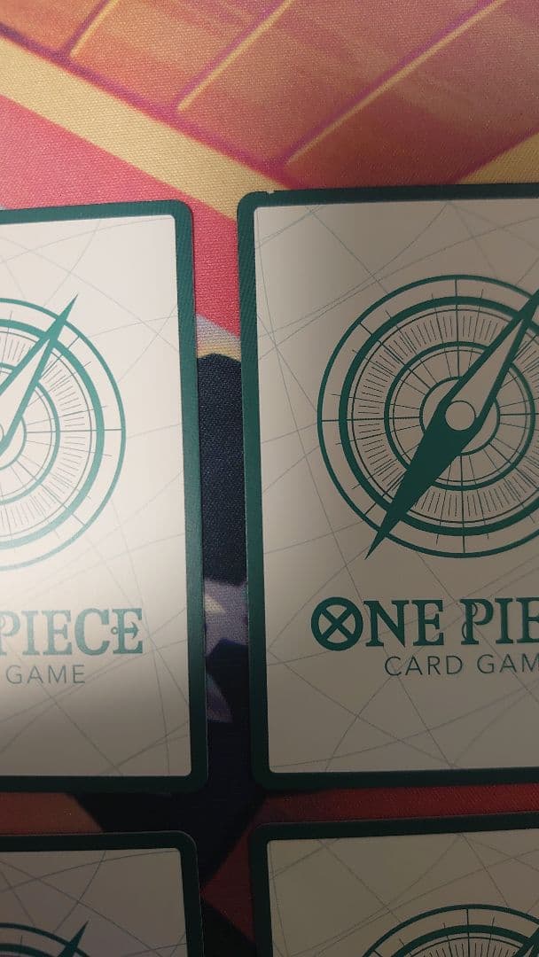 One Piece Card Game cards featuring Sabo, Luffy, Uta, and Akainu with gold borders in protective sleeve