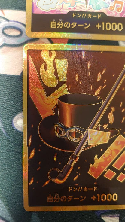 One Piece Card Game cards featuring Sabo, Luffy, Uta, and Akainu with gold borders in protective sleeve