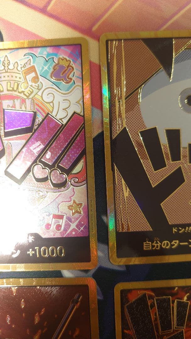 One Piece Card Game cards featuring Sabo, Luffy, Uta, and Akainu with gold borders in protective sleeve