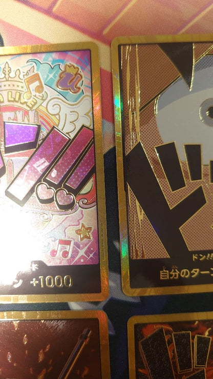 One Piece Card Game cards featuring Sabo, Luffy, Uta, and Akainu with gold borders in protective sleeve