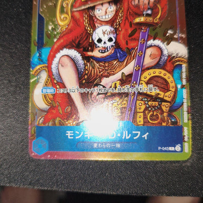 One Piece Monkey D. Luffy P-043 collectible card showing front with minor scratches and paint peeling on back
