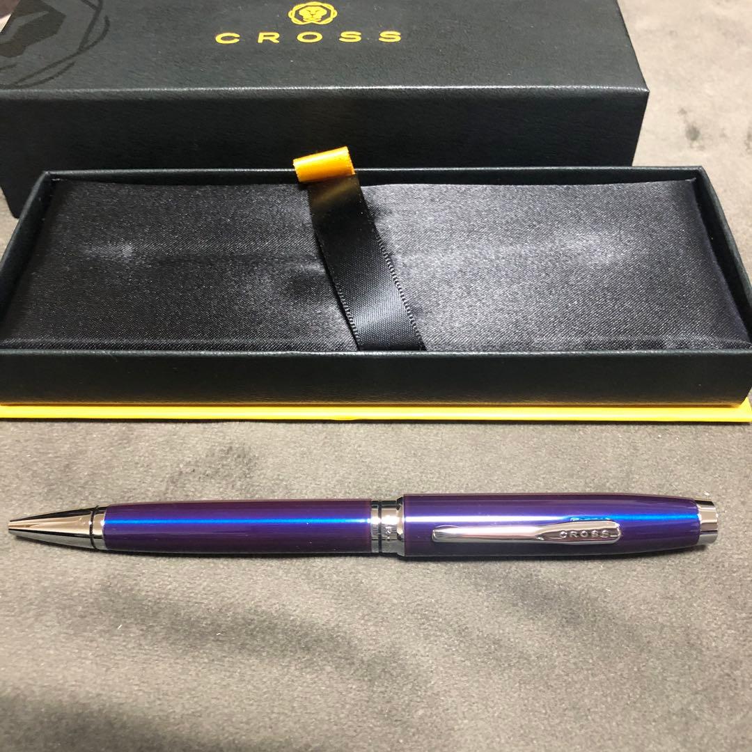 Blue metal-bodied Brand Crossball ballpoint pen with silver tip and visible scratch on glossy surface