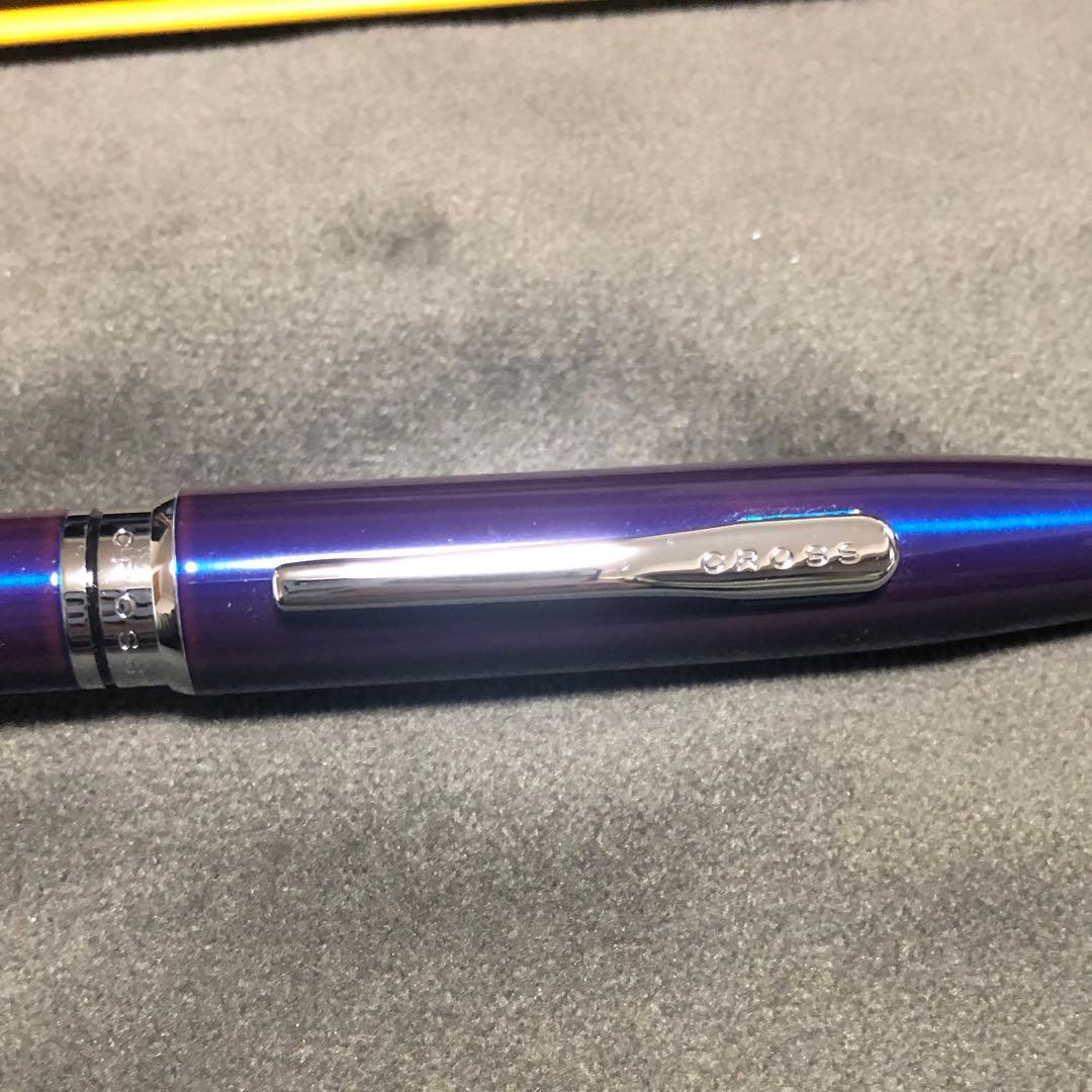 Blue metal-bodied Brand Crossball ballpoint pen with silver tip and visible scratch on glossy surface