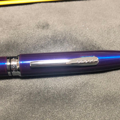 Blue metal-bodied Brand Crossball ballpoint pen with silver tip and visible scratch on glossy surface