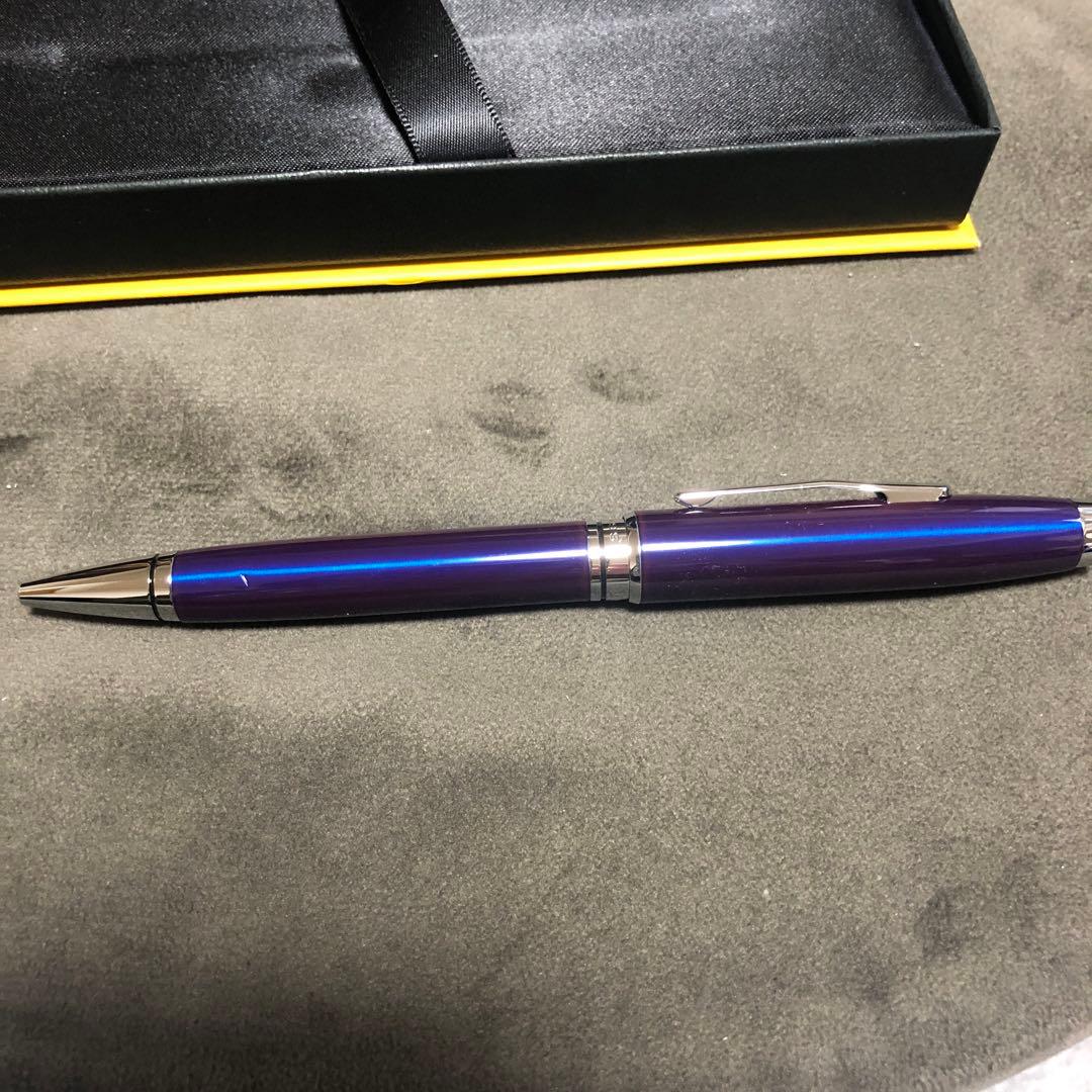Blue metal-bodied Brand Crossball ballpoint pen with silver tip and visible scratch on glossy surface