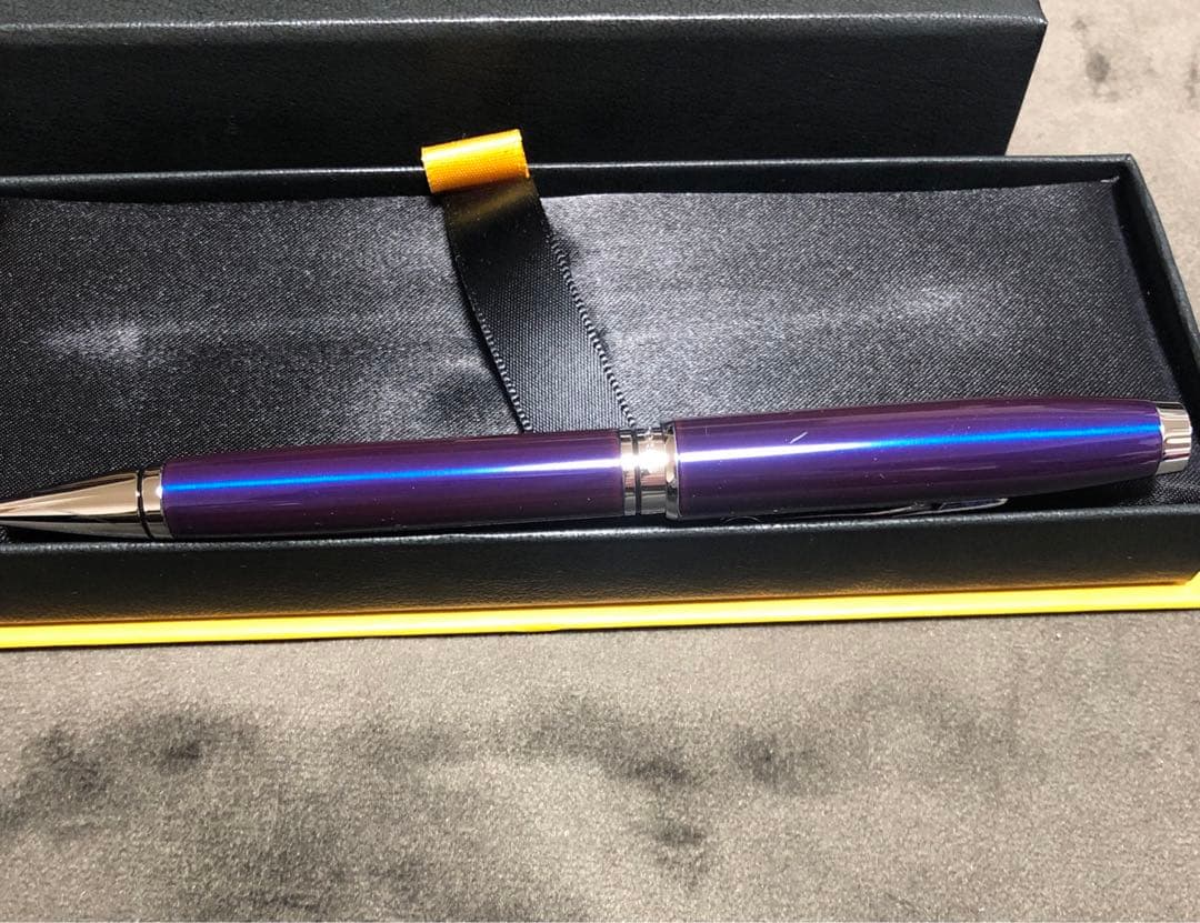 Blue metal-bodied Brand Crossball ballpoint pen with silver tip and visible scratch on glossy surface
