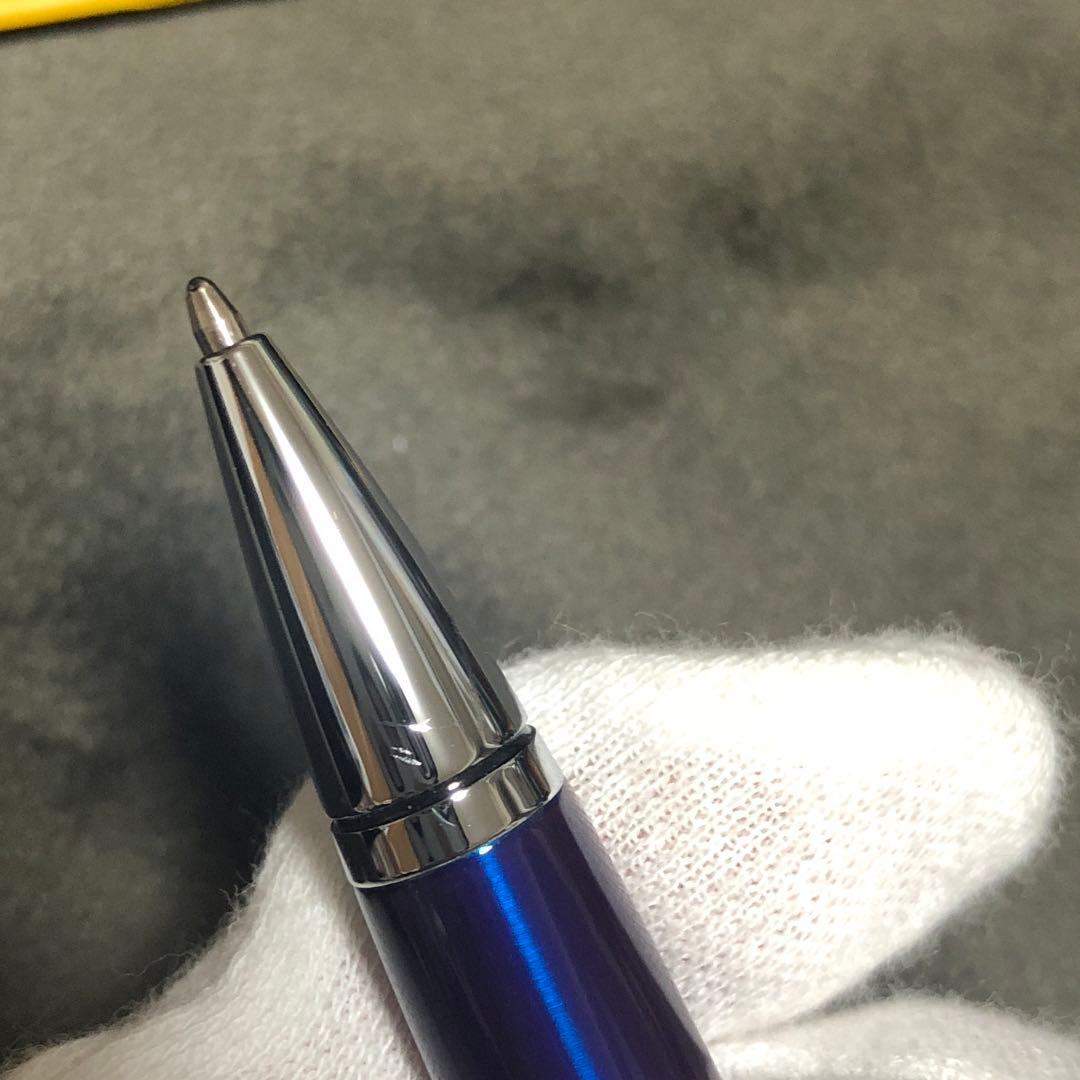 Blue metal-bodied Brand Crossball ballpoint pen with silver tip and visible scratch on glossy surface