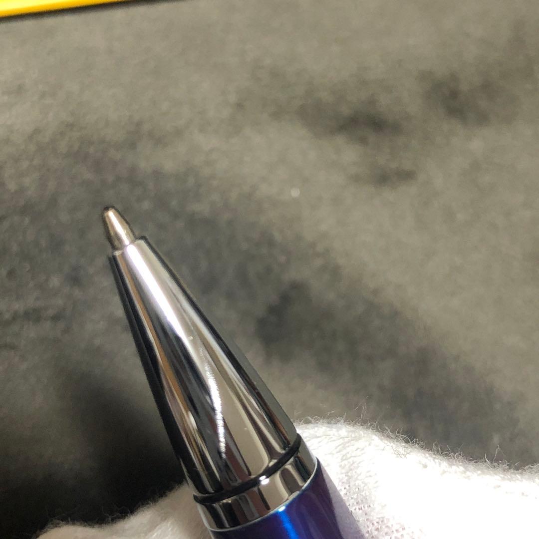Blue metal-bodied Brand Crossball ballpoint pen with silver tip and visible scratch on glossy surface