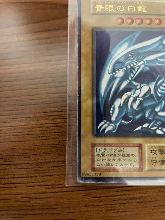 Yu-Gi-Oh Blue-Eyes White Dragon early edition trading card with visible wear and protective sleeve