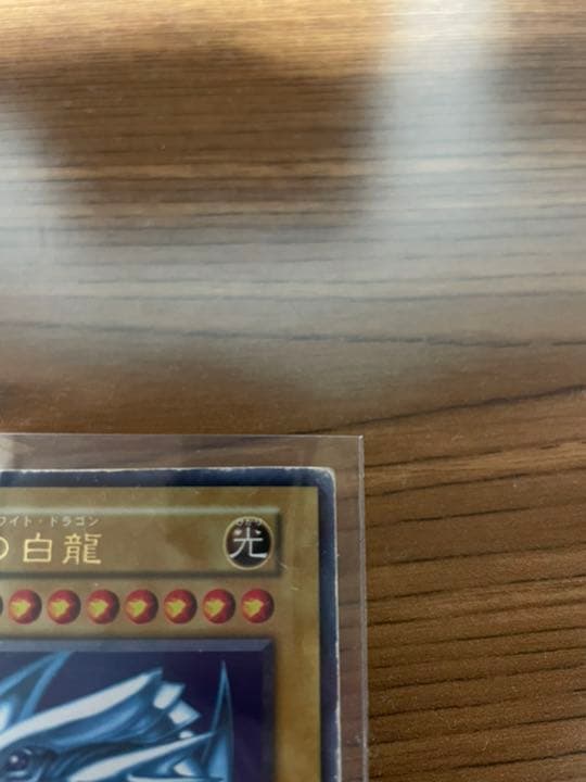 Yu-Gi-Oh Blue-Eyes White Dragon early edition trading card with visible wear and protective sleeve