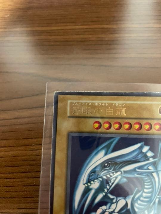 Yu-Gi-Oh Blue-Eyes White Dragon early edition trading card with visible wear and protective sleeve