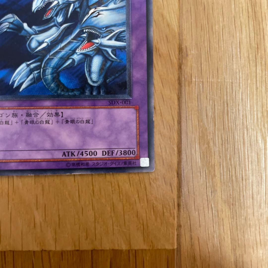 Yu-Gi-Oh Blue-Eyes Ultimate Dragon Ultra Rare SDX-001 card with visible scratches and chipping