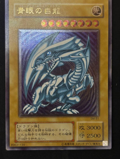 Used Yugioh Blue-Eyes White Dragon Ultra Rare SM-51 trading card from Japan with visible scratches and damage