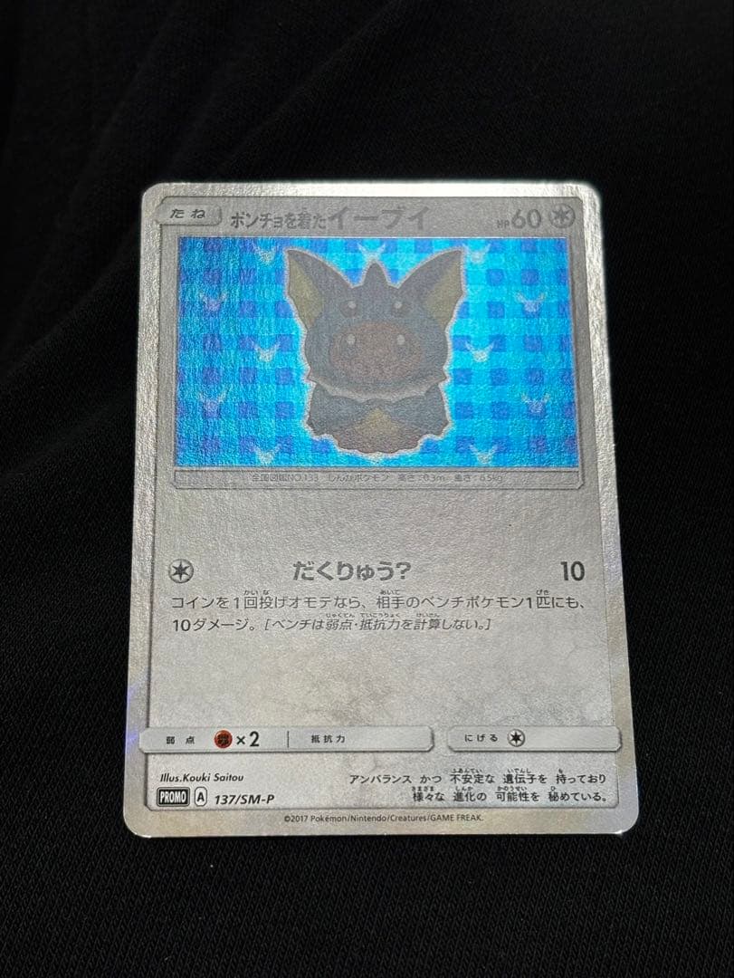 Pokemon promotional card featuring Eevee wearing a poncho with slight crease and small chip