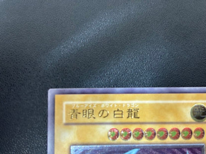 Blue-Eyes White Dragon relief card with 3000 attack power showing slight crease in upper right corner