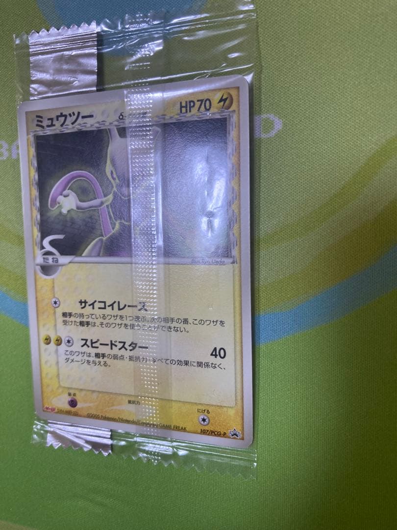 Unopened Meiji Mewtwo Delta Species 107/PCG-P Japanese promo collectible card with visible packaging wrinkles