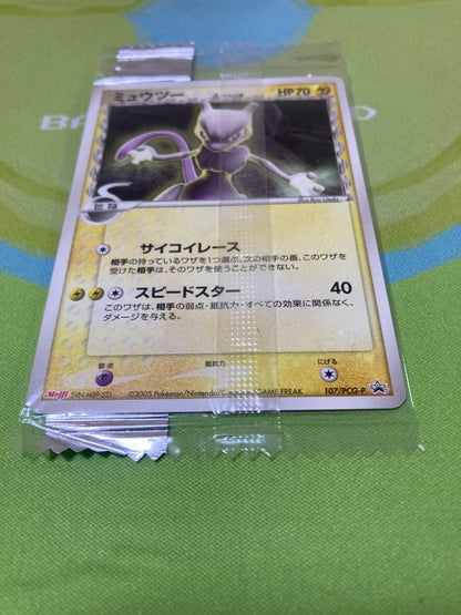 Unopened Meiji Mewtwo Delta Species 107/PCG-P Japanese promo collectible card with visible packaging wrinkles