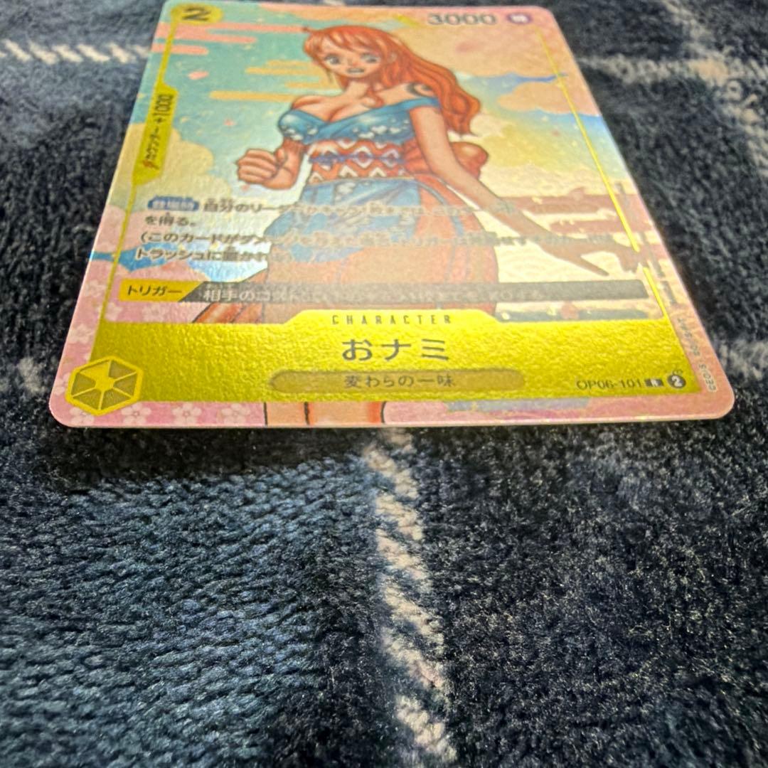 Used One Piece Card Game Nami R OP06-101 promotional card showing minor scratches and stored in protective sleeve