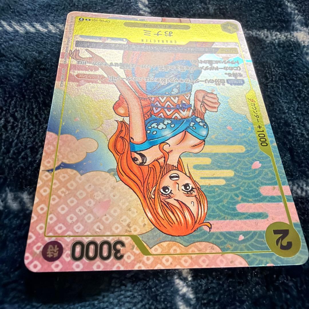 Used One Piece Card Game Nami R OP06-101 promotional card showing minor scratches and stored in protective sleeve