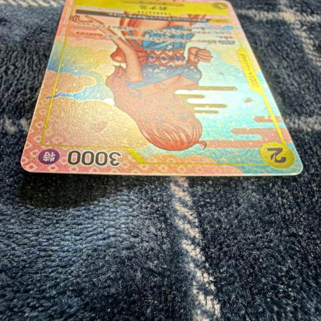 Used One Piece Card Game Nami R OP06-101 promotional card showing minor scratches and stored in protective sleeve