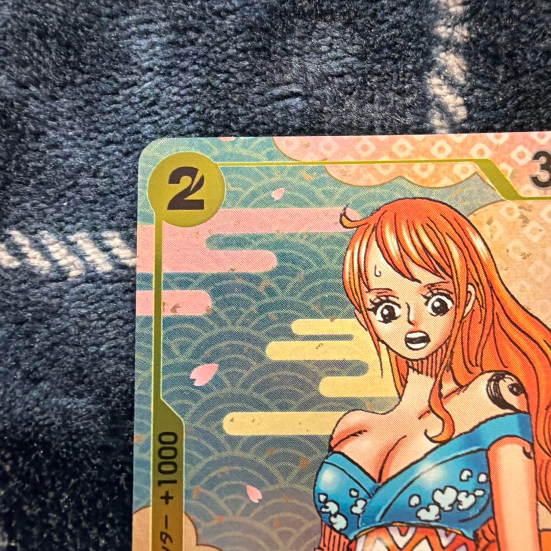 Used One Piece Card Game Nami R OP06-101 promotional card showing minor scratches and stored in protective sleeve