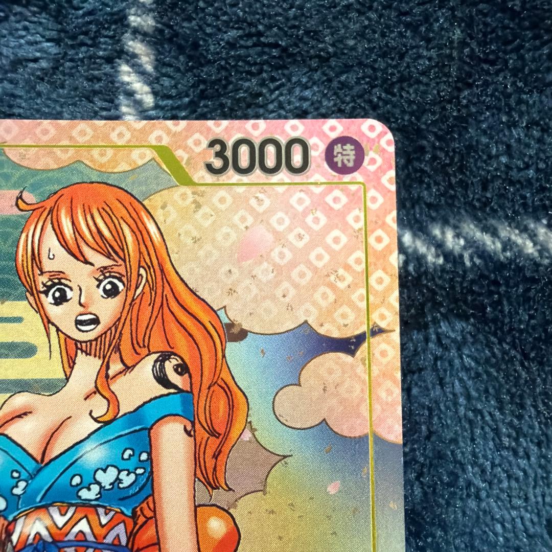 Used One Piece Card Game Nami R OP06-101 promotional card showing minor scratches and stored in protective sleeve
