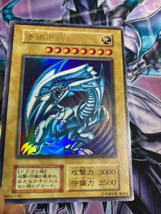 Sony Ultra Rare Blue-Eyes White Dragon Yu-Gi-Oh card showing light edge wear and scratch damage