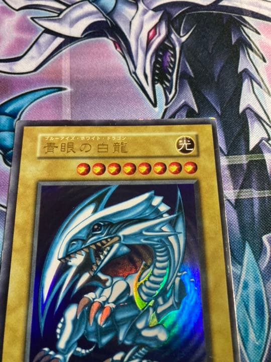 Sony Ultra Rare Blue-Eyes White Dragon Yu-Gi-Oh card showing light edge wear and scratch damage