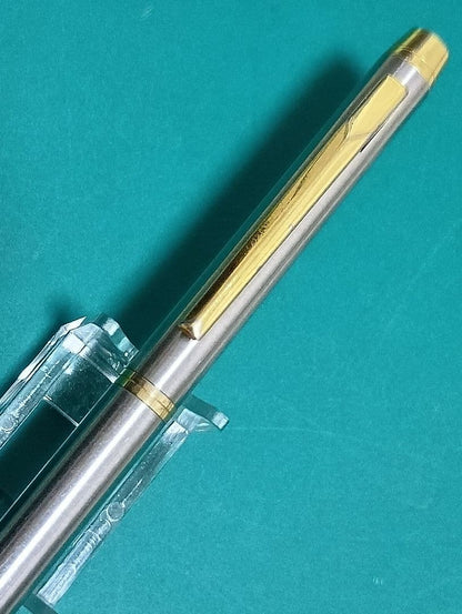 Used Unknown Brand twist ballpoint pen with silver and gold two-tone metal body and red CROSS refill