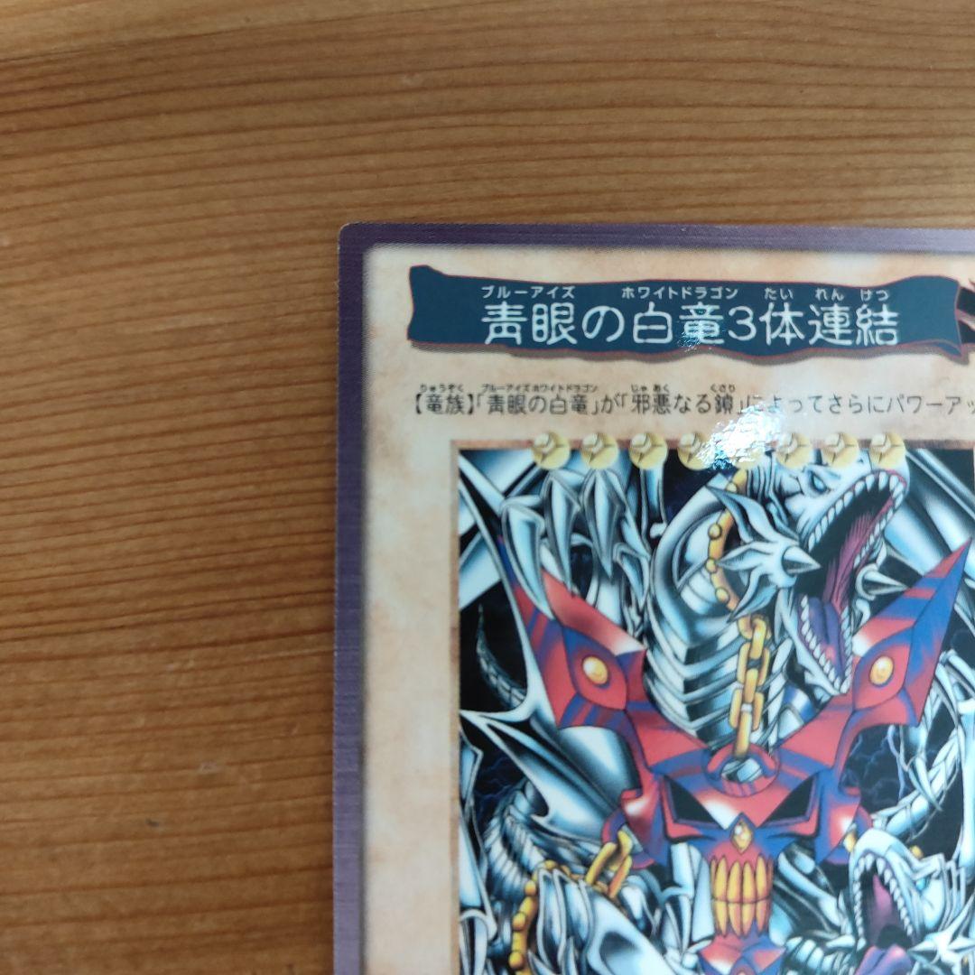 Bandai Yu-Gi-Oh! Blue-Eyes White Dragon three linked monster cards in storage sleeves showing minor wear