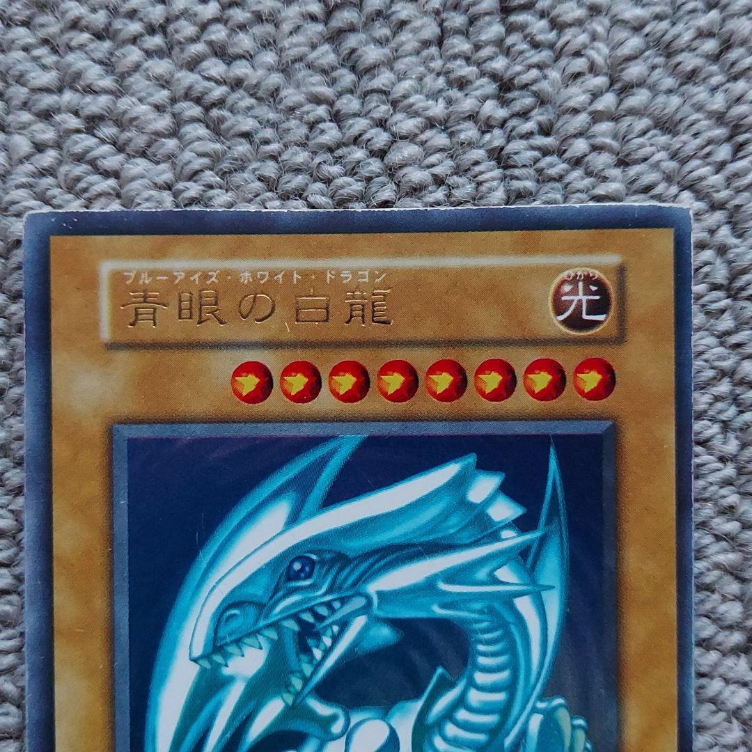 Bandai Yu-Gi-Oh Blue-Eyes White Dragon Ultra Rare Monster Card showing small scratches and frame misalignment