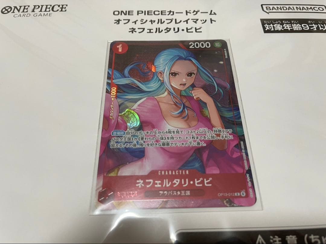 One Piece Badge Neferutari Vivi character playmat with promo card made of polyester and rubber folded in packaging