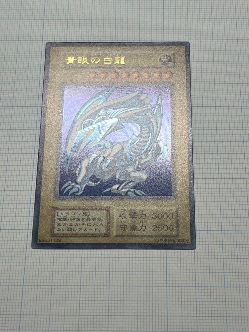 Yugioh Blue-Eyes White Dragon Ultra Rare trading card with light surface scratches and a small dent in the center