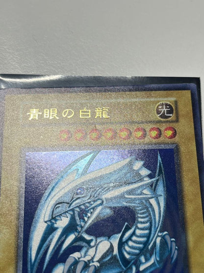 Yugioh Blue-Eyes White Dragon Ultra Rare trading card with light surface scratches and a small dent in the center