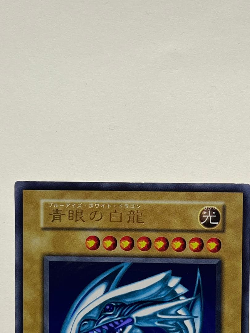 Yugioh Blue-Eyes White Dragon Ultra Rare trading card with light surface scratches and a small dent in the center
