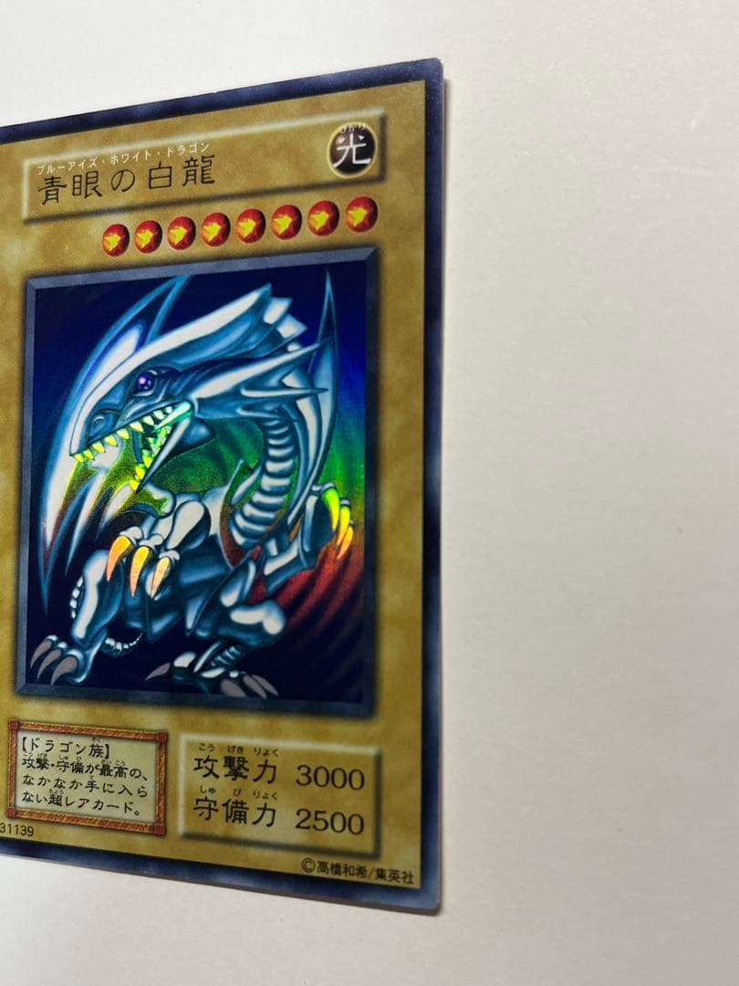 Yugioh Blue-Eyes White Dragon Ultra Rare trading card with light surface scratches and a small dent in the center