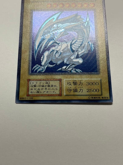 Yugioh Blue-Eyes White Dragon Ultra Rare trading card with light surface scratches and a small dent in the center