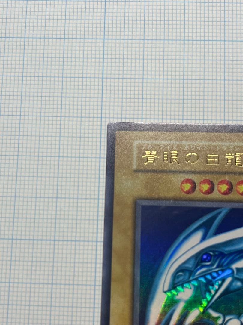 Yugioh Blue-Eyes White Dragon Ultra Rare trading card with light surface scratches and a small dent in the center